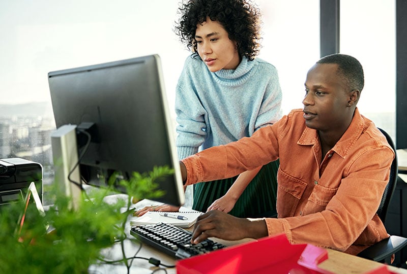 two coworkers looking at a monitor