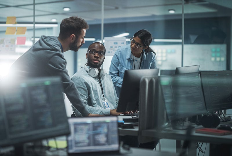 three coworkers standing around a computer