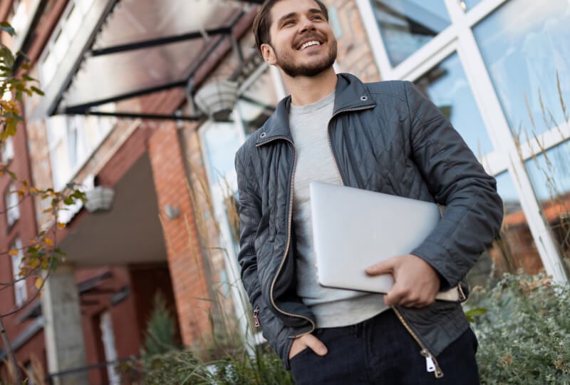 a man holding a laptop walking outside