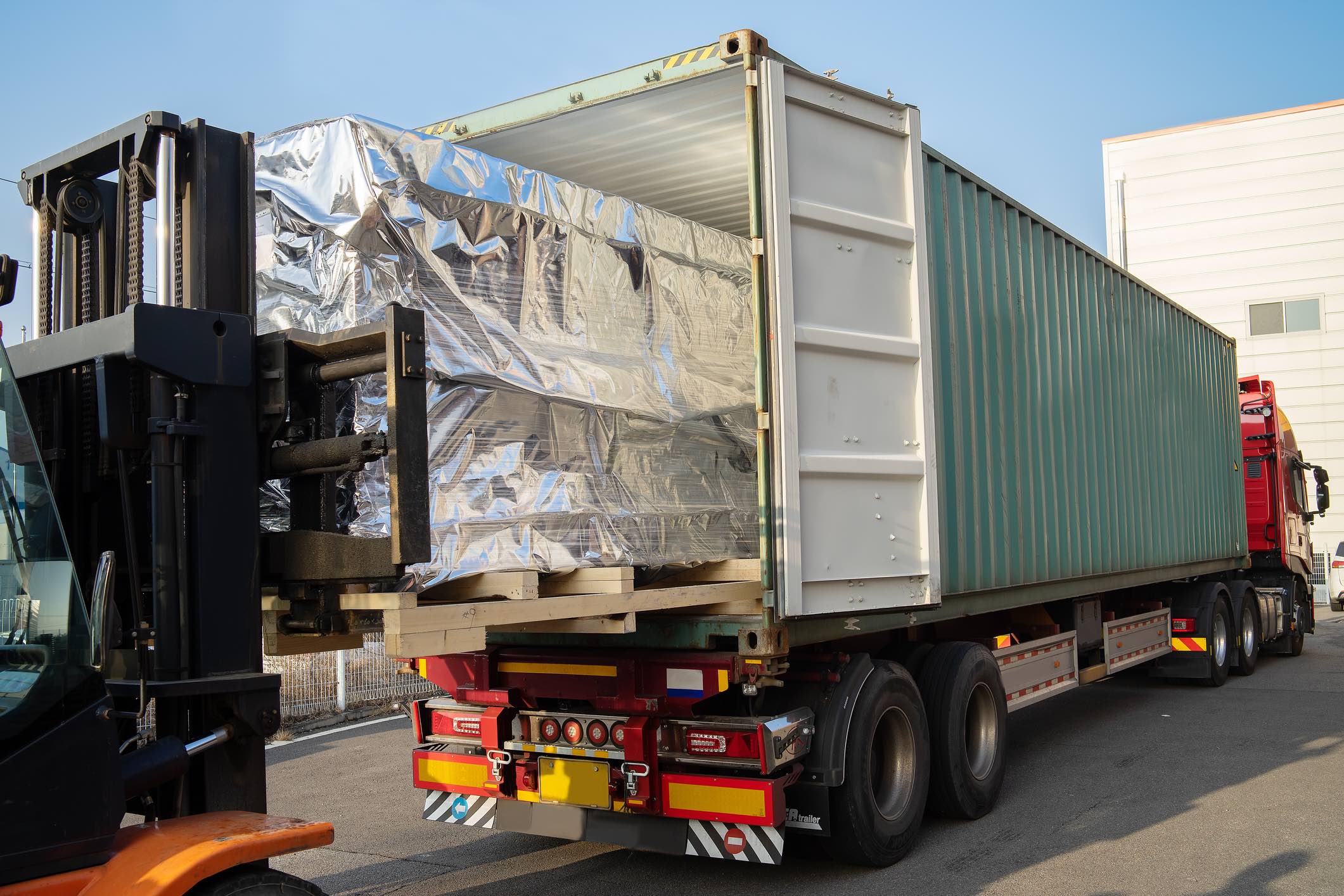 Pallets being loaded into the back of a box truck.