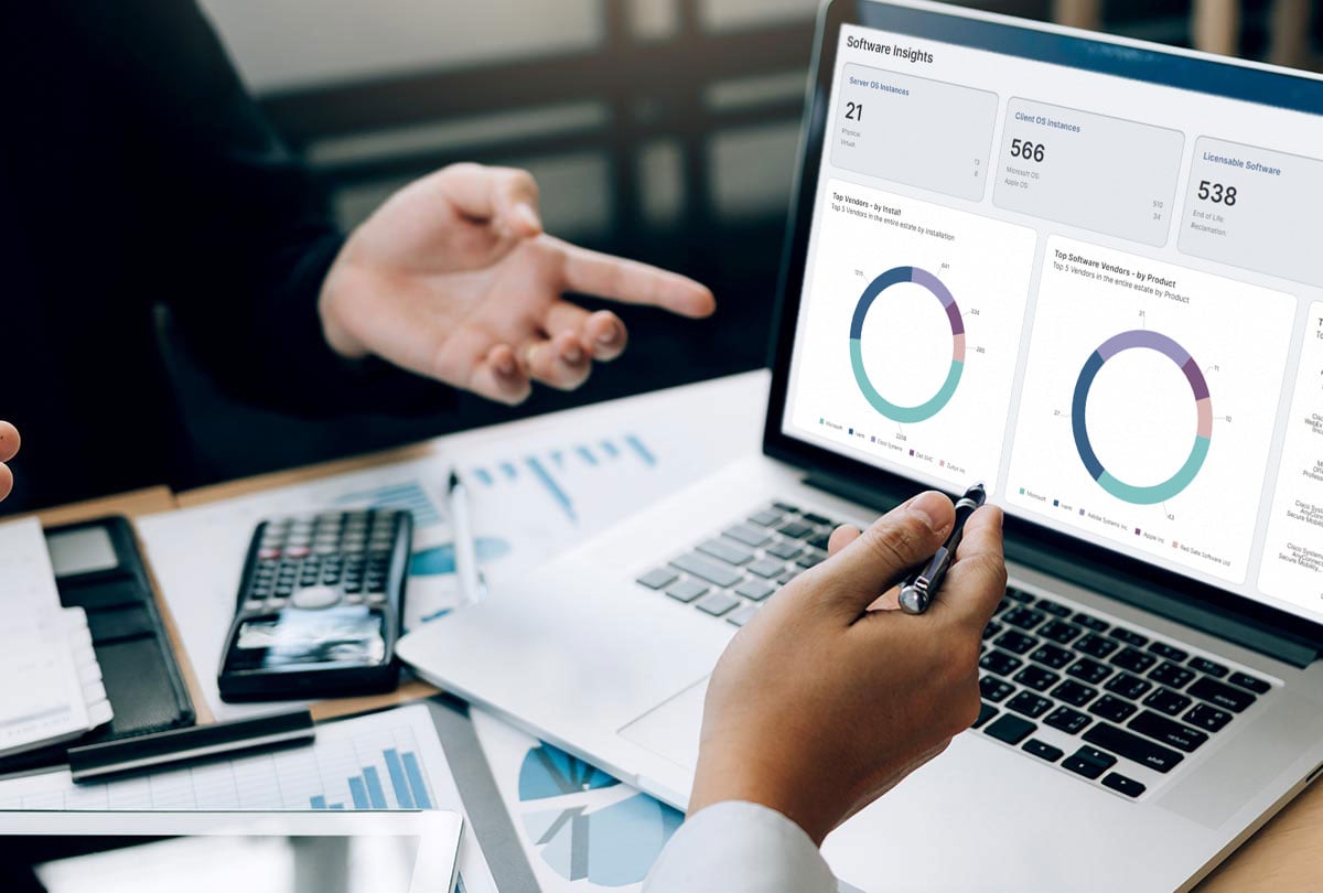 The hands of two separate people gesturing towards a laptop screen with the Neurons for Spend Intelligence dashboard displayed on it.