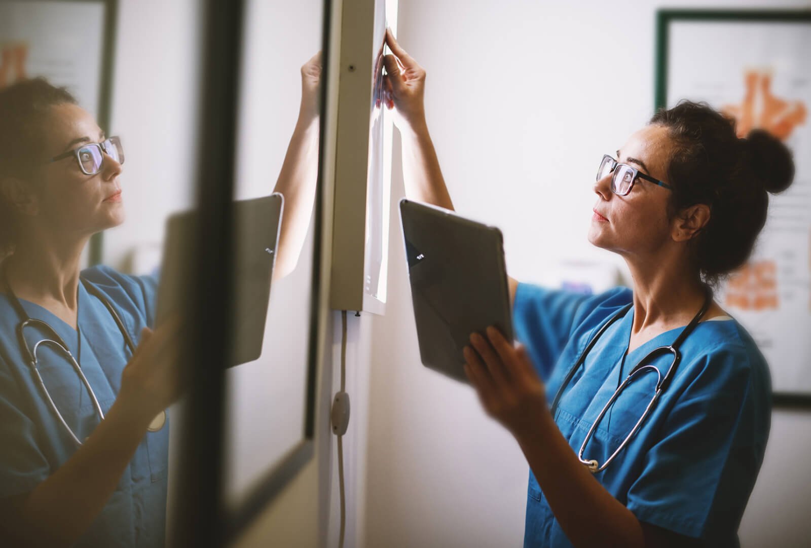woman nurse holding ipad looking at board