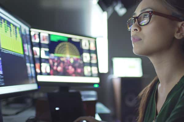 woman looking up at multiple monitors